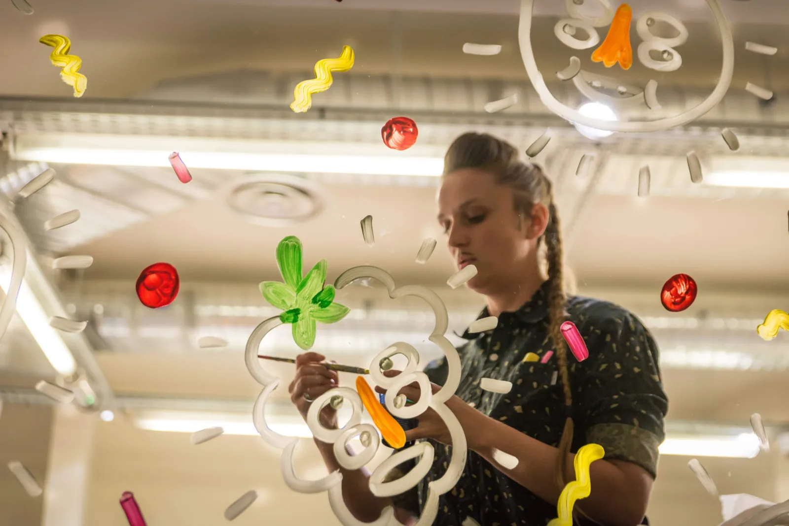 Artiste peignant une vitrine à la main pendant la soirée de lancement de l'opération Naturaliart