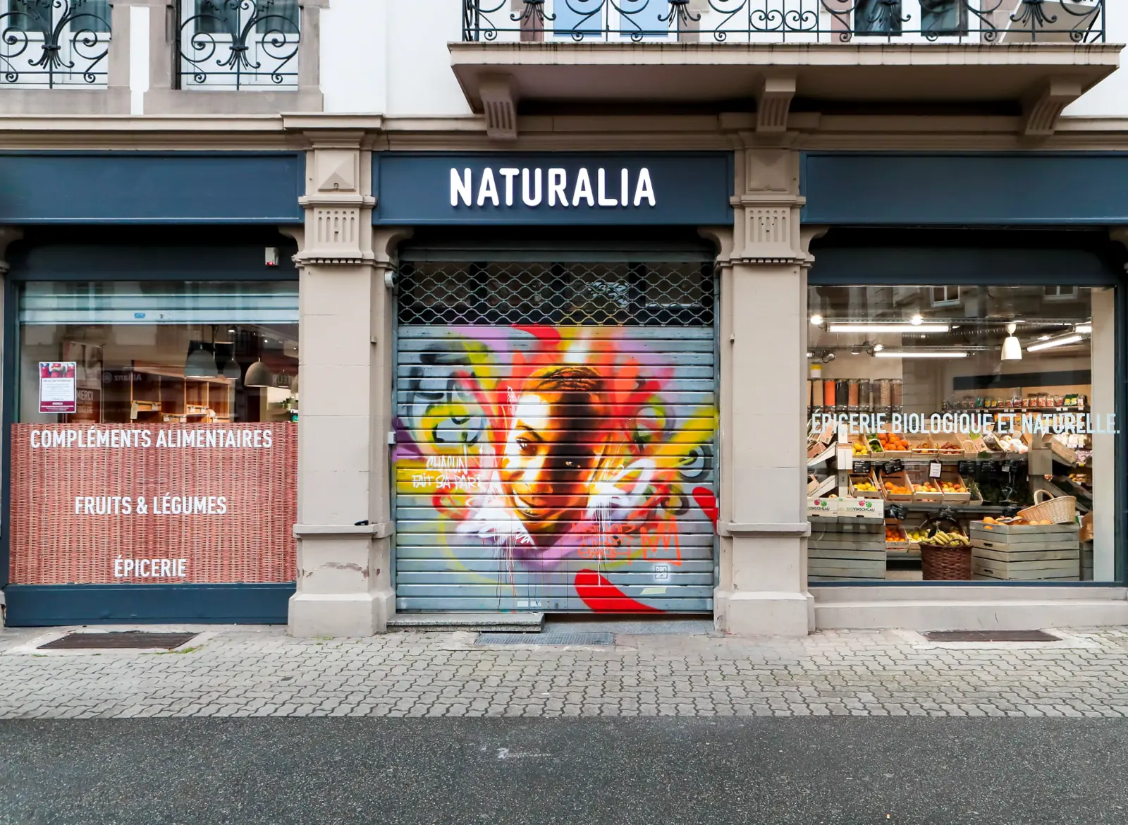 Magasin Naturalia à Strasbourg avec portrait street art coloré peint sur le rideau de fer